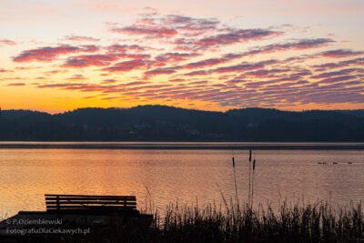 Widok na jezioro i chmury podświetlone na czerwono porannym słońcem.