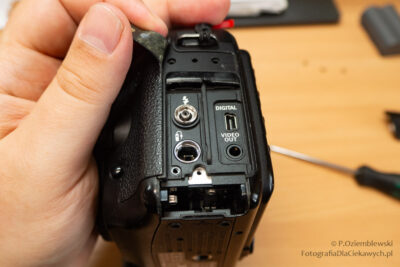 Odkręcone śrubki i wyjęta pastylkowa bateria z uchwytem.